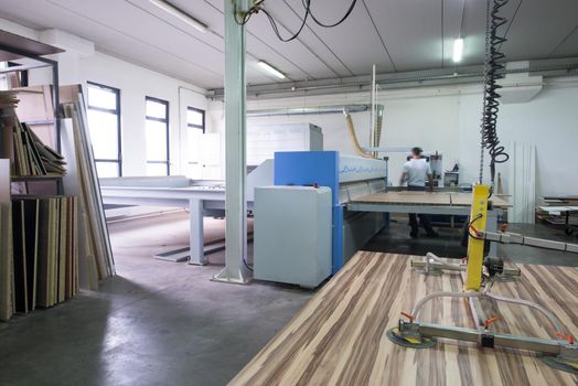 Young worker works in a factory for the production of wooden furniture