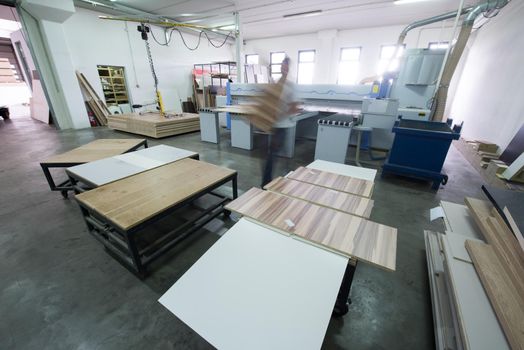 Young worker works in a factory for the production of wooden furniture