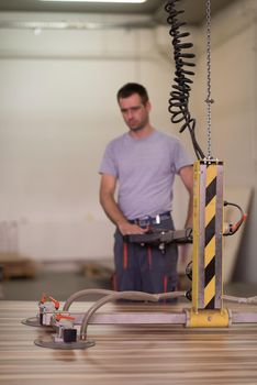 Young worker works in a factory for the production of wooden furniture