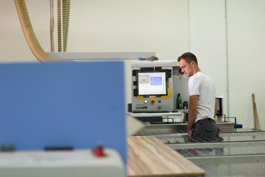 Young worker works in a factory for the production of wooden furniture