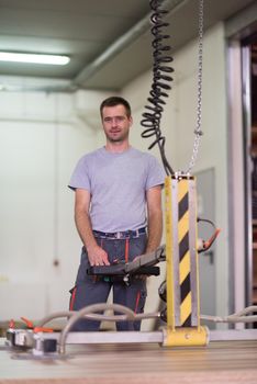 Young worker works in a factory for the production of wooden furniture