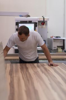 Young worker works in a factory for the production of wooden furniture