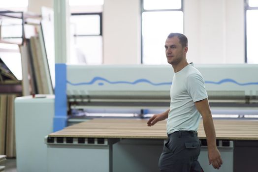 Young worker works in a factory for the production of wooden furniture