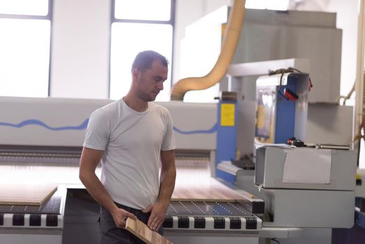 Young worker works in a factory for the production of wooden furniture