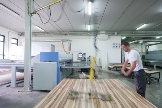 Young worker works in a factory for the production of wooden furniture