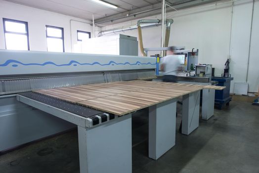 Young worker works in a factory for the production of wooden furniture