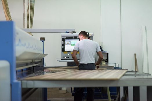 Young worker works in a factory for the production of wooden furniture