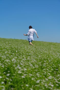 Young happy woman in green field with blue sky in background