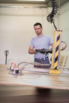 Young worker works in a factory for the production of wooden furniture