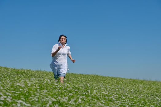 Young happy woman in green field with blue sky in background