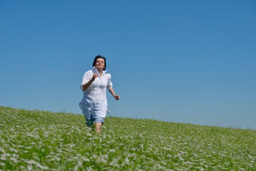 Young happy woman in green field with blue sky in background