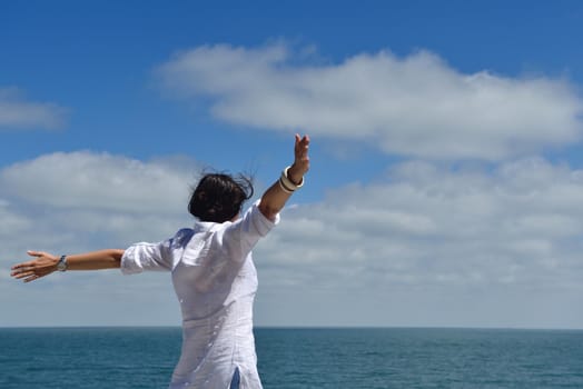 Happy  young woman with spreading arms, blue sky with clouds in background  - copyspace