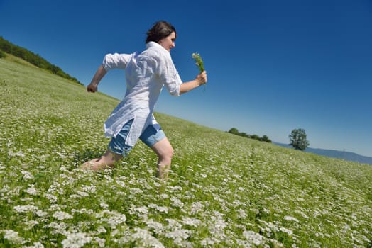 Young happy woman in green field with blue sky in background