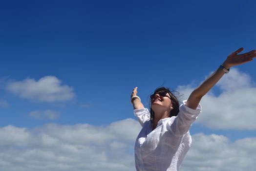 Happy  young woman with spreading arms, blue sky with clouds in background  - copyspace