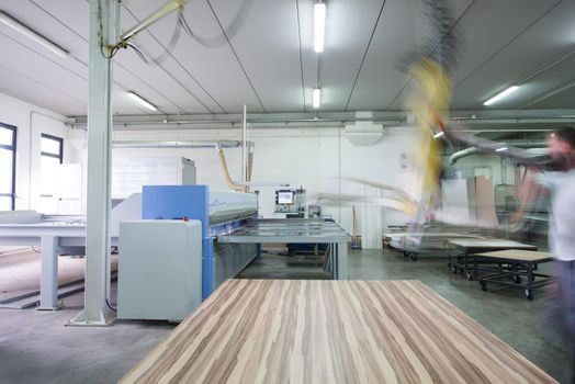 Young worker works in a factory for the production of wooden furniture