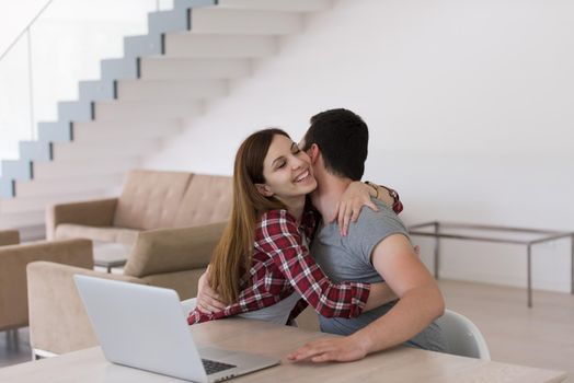 happy young couple buying online using laptop a computer and a credit card in their luxury home villa