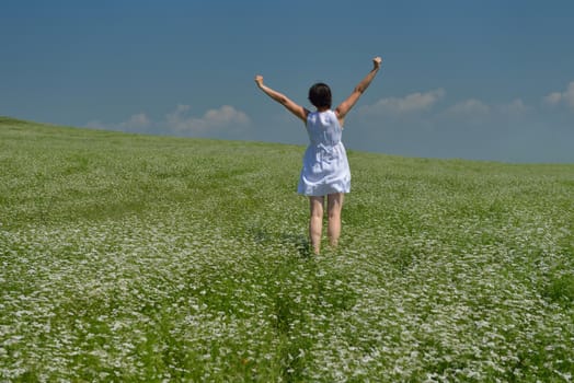 Young happy woman in green field with blue sky in background