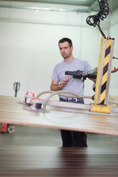 Young worker works in a factory for the production of wooden furniture