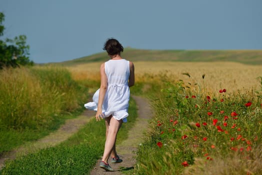 Young happy woman in green field with blue sky in background