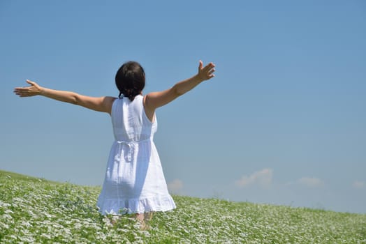 Young happy woman in green field with blue sky in background