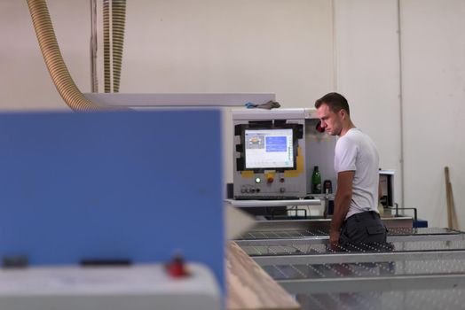 Young worker works in a factory for the production of wooden furniture