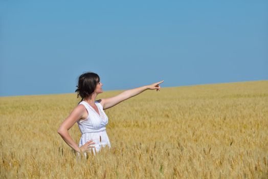 Young woman standing jumping and running  on a wheat field with blue sky the background at summer day representing healthy life and agriculture concept