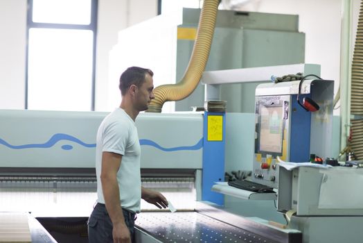 Young worker works in a factory for the production of wooden furniture