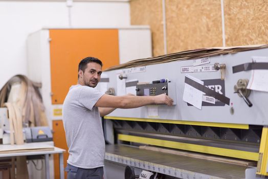 Young worker works in a factory for the production of wooden furniture