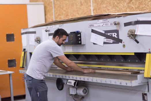 Young worker works in a factory for the production of wooden furniture