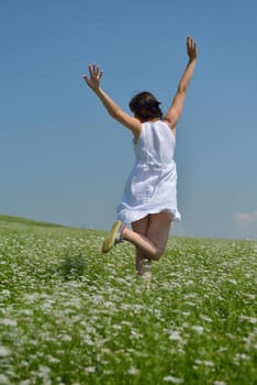 Young happy woman in green field with blue sky in background