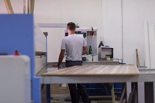 Young worker works in a factory for the production of wooden furniture