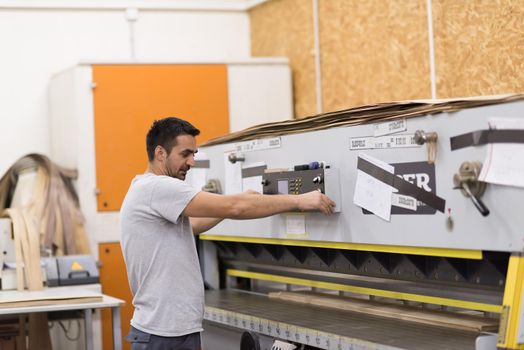 Young worker works in a factory for the production of wooden furniture