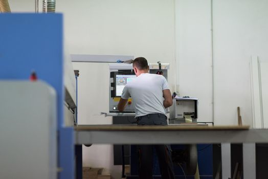 Young worker works in a factory for the production of wooden furniture