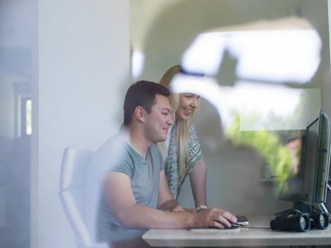 young man and woman operators of security systems looking at CCTV footage at desk in office