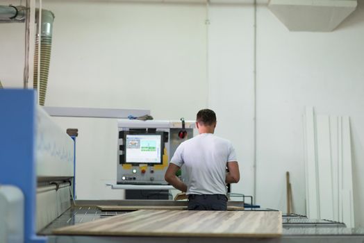 Young worker works in a factory for the production of wooden furniture