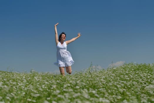 Young happy woman in green field with blue sky in background