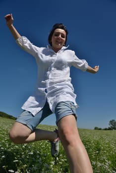 Young happy woman in green field with blue sky in background