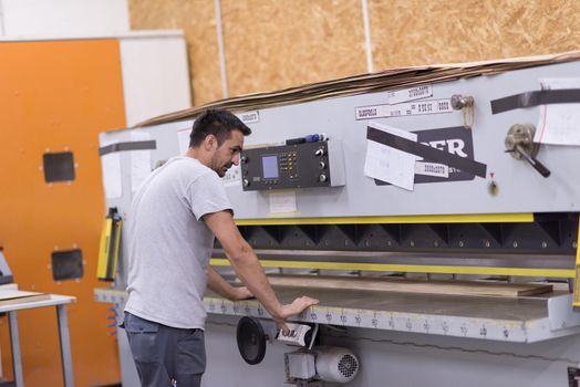 Young worker works in a factory for the production of wooden furniture