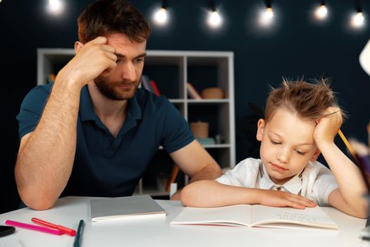 Dad and son doing school homework together sitting at the table