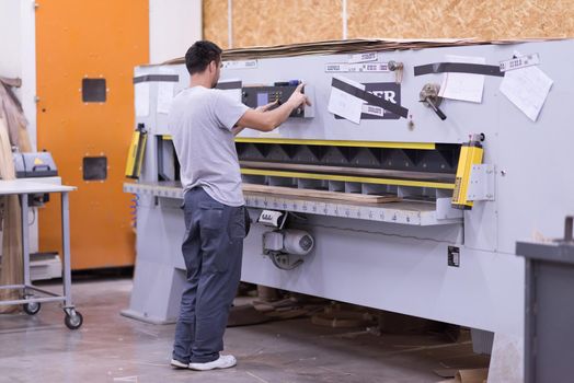 Young worker works in a factory for the production of wooden furniture