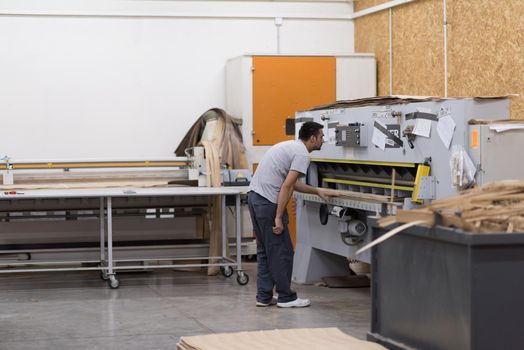 Young worker works in a factory for the production of wooden furniture