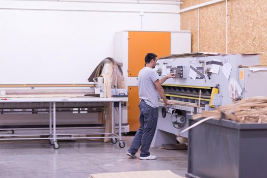 Young worker works in a factory for the production of wooden furniture