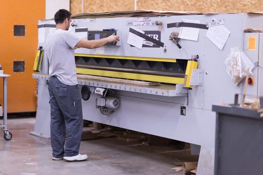 Young worker works in a factory for the production of wooden furniture