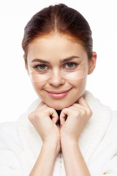 Woman in white robe posing fun skin care patches on face. High quality photo