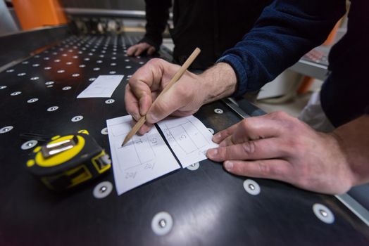 two young carpenters calculating and programming a cnc wood working machine in workshop. wood workers preparing a computer program for CNC machine at big modern carpentry