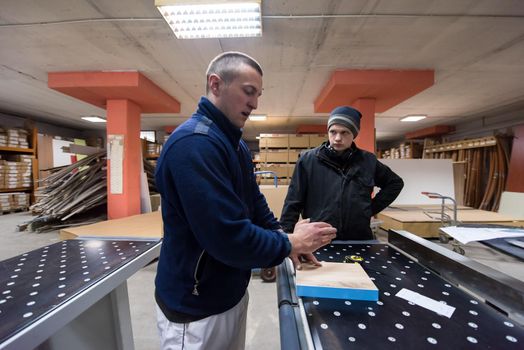 two young carpenters calculating and programming a cnc wood working machine in workshop. wood workers preparing a computer program for CNC machine at big modern carpentry