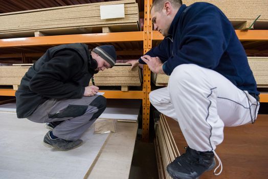 two young carpenters writing new prices while working together in big modern carpentry High quality wood concept