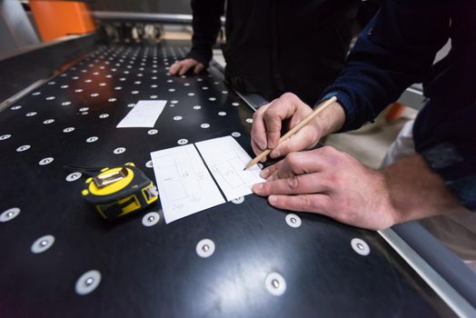 two young carpenters calculating and programming a cnc wood working machine in workshop. wood workers preparing a computer program for CNC machine at big modern carpentry