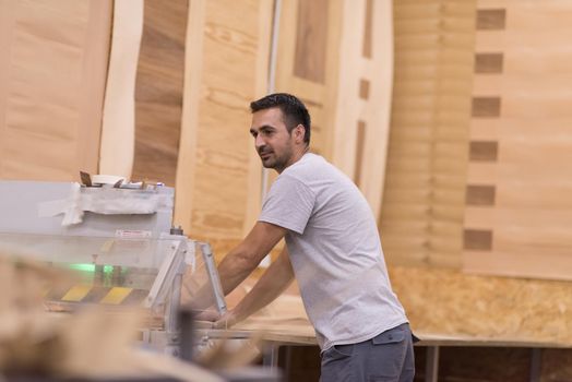 Young worker works in a factory for the production of wooden furniture