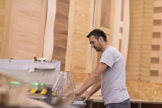 Young worker works in a factory for the production of wooden furniture